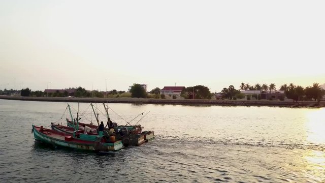 Aerial shot of fishing boast on the Prek Kampong river in Kampot, Cambodia with Bokor National Park in the distance at sunset.