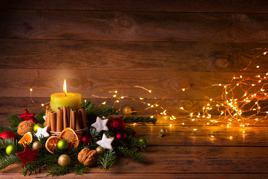 Festive Christmas or Advent Background  -  Burning candle with natural decoration on rustic wood