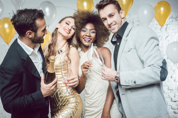 Party people with drinks celebrating new year or a birthday party together in a club