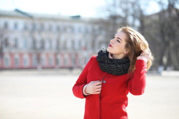 Fototapeta premium Pretty girl on a walk in red coat in the city