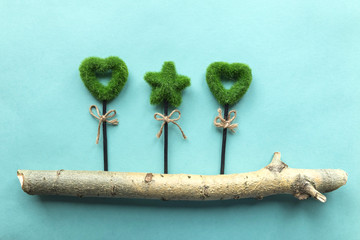 Flatlay eco green handmade stick with plants on the tree trunk on the light blue background