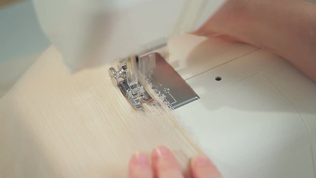 Closeup of a fashion designer woman sews on a sewing-machine an evening silk dress