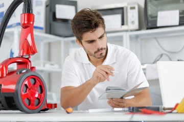 repairman diagnosing vacuum cleaner in his workshop