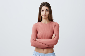 Beautiful young unhappy Caucasian brunette girl with long hairstyle in fashionable outfit crossing...