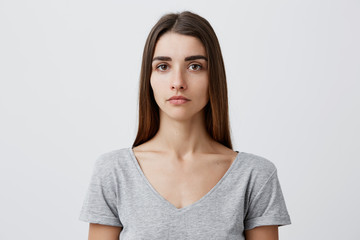 Close up of young handsome charming caucasian girl with long brown hair in gray t-shirt looking in...
