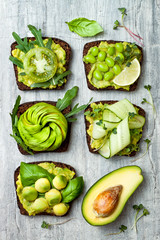 Fresh avocado toasts with different toppings. Healthy vegetarian breakfast with rye wholegrain sandwiches