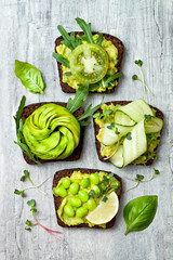 Fresh avocado toasts with different toppings. Healthy vegetarian breakfast with rye wholegrain sandwiches
