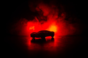 The car in the shadows with glowing lights in low light, or silhouette of sport car dark background