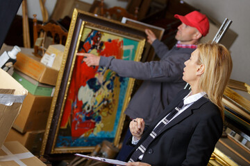 man holding and showing a painting to auctioneer before auction - obrazy, fototapety, plakaty