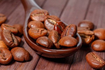 Grains of coffee close-up. Coffee beans are located on a spoon among the wooden texture. Coffee...
