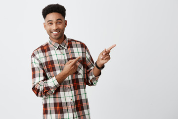 Close up portrait of young good-looking dark-skinned man with stylish dark afro hair in checkered...