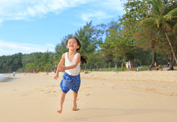 Smiling little child girl running on the beach in summer times.