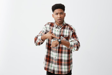 We're late for meeting. Young good-looking tan-skinned unhappy guy with afro hairstyle in checkered...