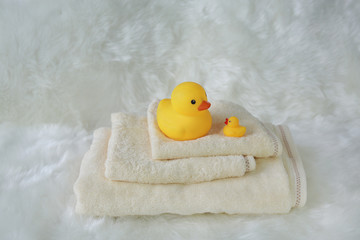 Children's bath products and hygiene items on white fur. Towel with yellow rubber duck.