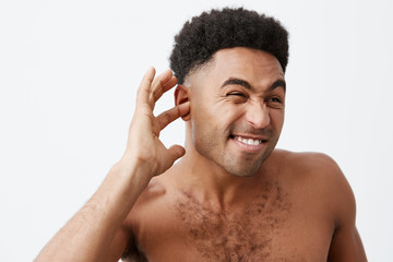 Mature good-looking black-skinned african male with curly hair and naked torso trying to get water from ears after bath in early morning. Man getting ready for work.