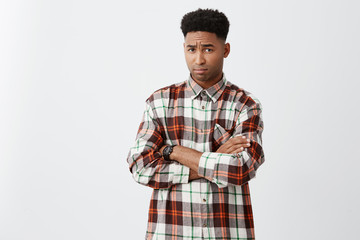 Portrait of unhappy young attractive black-skinned man with curly hair in casual checkered shirt...