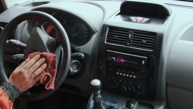Man wipes the surface of dashboard panel with polish
