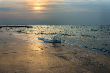 Beach sunset above the sea. Sunset at twilight with waves and sun reflection over the water....