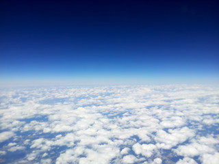 top view of white clouds from a airplane, on a background of the clear blue sky