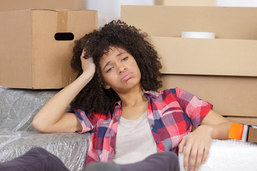 frustrated woman sitting by cardboard boxes in new house