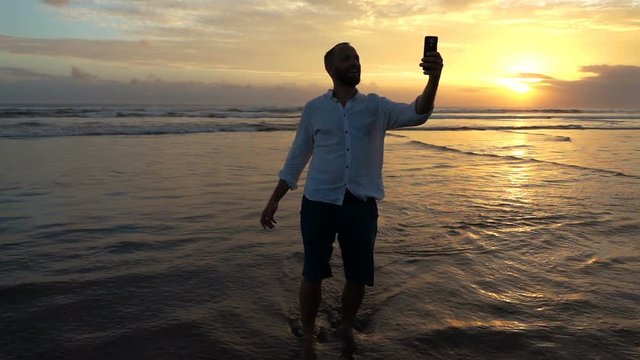 Happy man taking selfie photo  on beach during sunset, super slow motion 240fps
