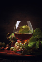 Cognac In Glass, Grapes And Vine, Old Wooden Background, Selective Focus
