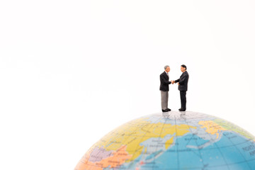 business miniature people handshaking on the globe isolated on white background