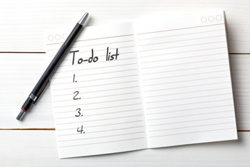 Opened personal organizer with a to do list. on white wooden background