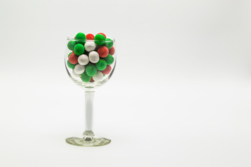 wine glass filled with colorful Christmas candy isolated on a plain background