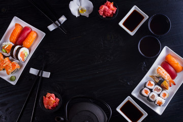 Japanese sushi dish scene on black wooden background, flat lay frame with copy space