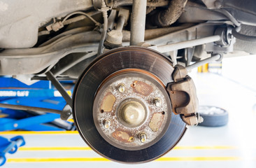 Closeup disc brake of the vehicle for repair, in process of new tire replacement. Car brake repairing in garage