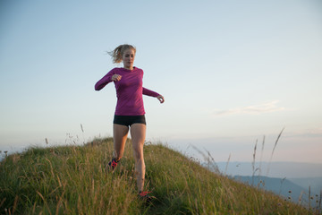 Woman runs on a top of the mountains with mountain range in background