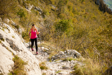 Naklejka na ściany i meble Beautiful young woman hiking in mountains on a sunny summer afternoon