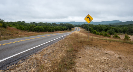 Low Angle Shot of Country Road With Yellow TRaffic Sign in the Foreground