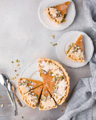 American pumpkin pie, stitched with seeds, powdered sugar and ice cream on a gray light concrete background. Copy Space. View blank space for text. Place for text. photo with hands. Flat lay, top view