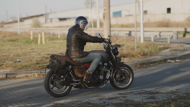 Man Riding old custom cafe-racer Motorcycle on Country Road at autumn sunny day