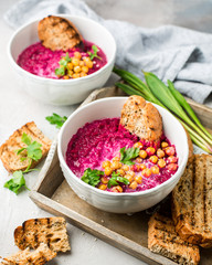 Beetroot cream soup with coconut milk, baked chickpeas, sesame, parsley on a gray concrete background. Baked chickpeas with spices. Useful dietary snack and lunch. Place for text. Flat lay, top view