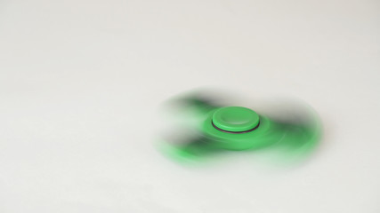 Green fidget spinner turns and stops on white background