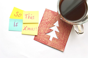 Cup of coffee on a Christmas card and sticky notes over a white background