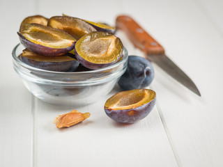 Vintage knife with a bowl of sliced ripe plums.