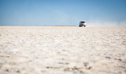 Fototapeta na wymiar A four wheel drive vehicle driving over the salt pans in Botswana