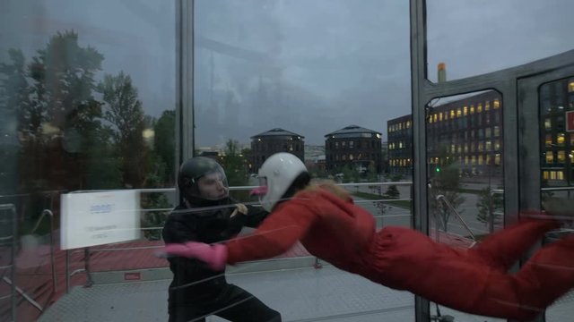 Instructor teaching young woman skydiving. Extreme parachuting in wind tunnel