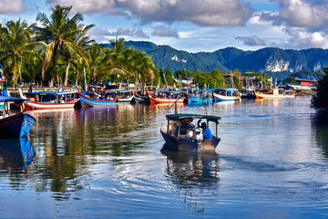 Fototapeta premium Lokalny rybak wypływa łodzią z parku łodzi na morze na ryby. Tradycyjne kolorowe azjatyckie łodzie rybackie w wiosce rybackiej. Wyspa Langkawi, Malezja.