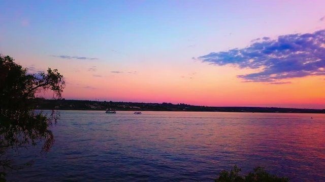 Aerial drone shot rising up from behind trees next to Lake Paranoa at dusk
