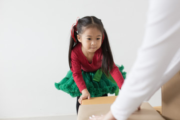 Attractive Asian Girl try to move a box at home. Kid holding Box with Attractive smiling. Kid with Happy Emotion.