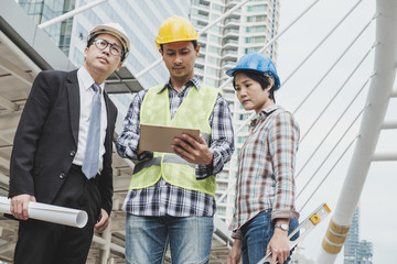 Multiethnic business man or engineer or architect and technician with business partner on meeting and discussion while using on digital tablet, smartphone on modern city. Startup or teamwork concept.