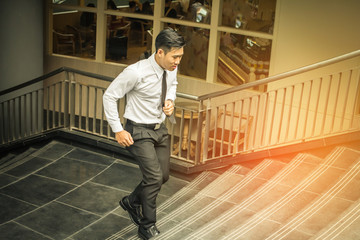 Asain business young man  running fast upstairs. outdoors.