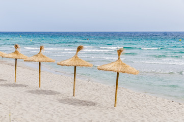 Straw umbrellas on sand beach.