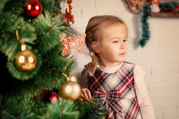 Pretty little child near Christmas tree.