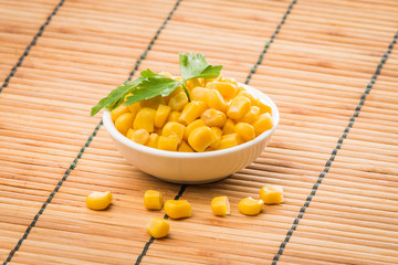 cooked sweet corn seeds in a  bowl on a wooden table. canned corn
